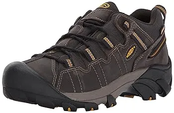 The image shows a single black and brown hiking shoe with laces and a robust outsole.
